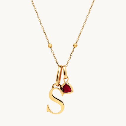 custom gold initial and birthstone necklace on beige background – elegant and symbolic