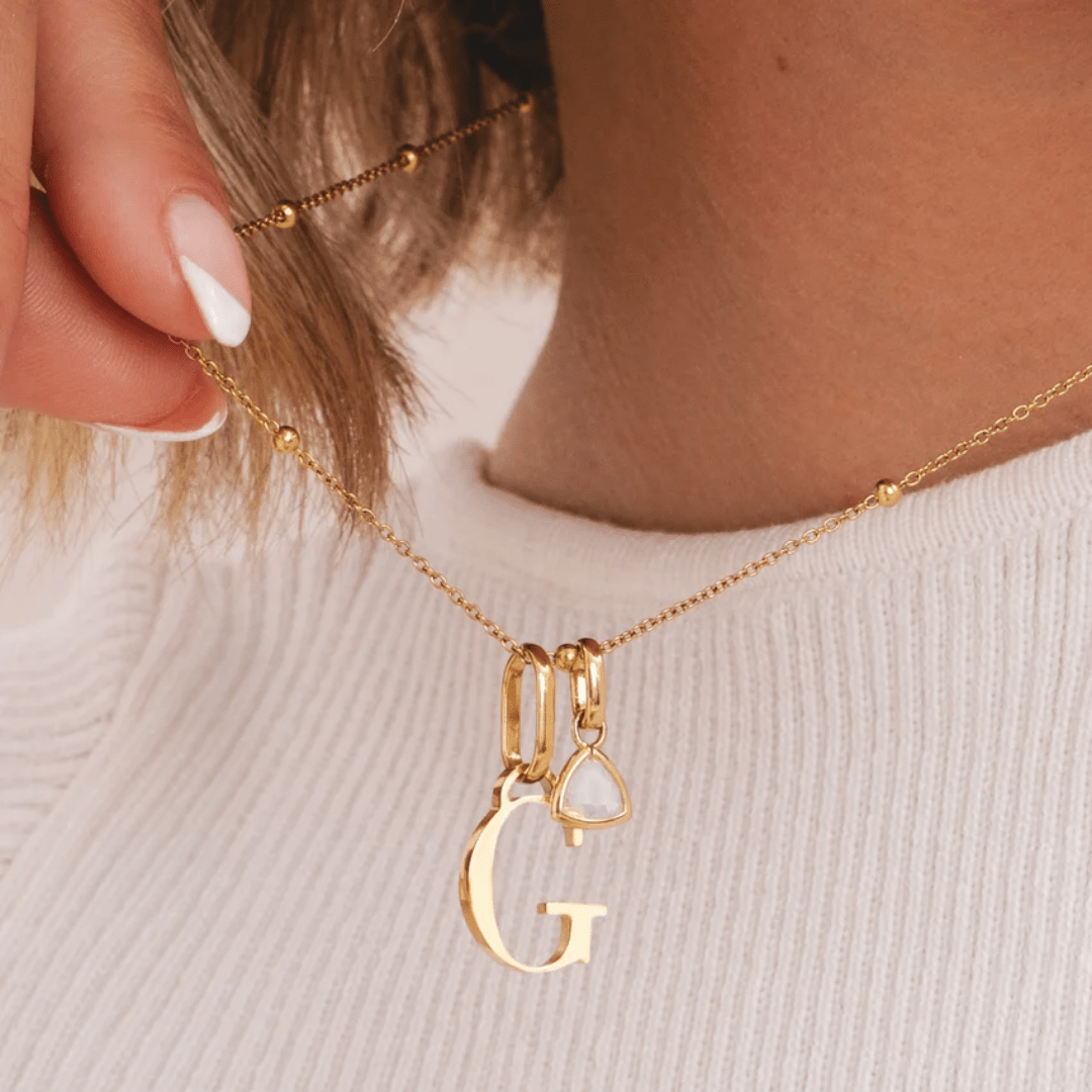 gold initial charm necklace with red birthstone – worn on neck for everyday style